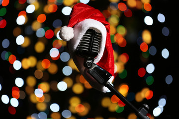 Old microphone decorated with Christmas hat against defocused lights