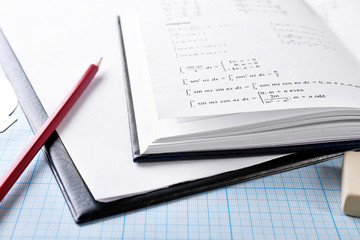 School supplies and textbook on mathematics close up