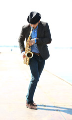 Young man playing on saxophone on the riverside