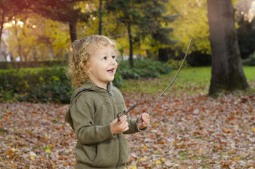 Cute Caucasian child playing in park with sticks, healthy lifestyle