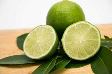 lemon and leaves on wooden cutting board on white