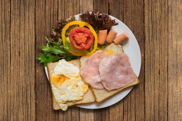 Sandwiches with salad, ham, chicken sausages and tomatoes on wooden table