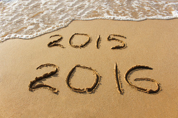 2015 and 2016 year written on sandy beach sea. 