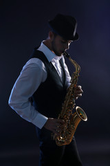 Fototapeta na wymiar Elegant saxophonist plays jazz on dark background