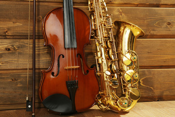 Naklejka premium Violin and saxophone on wooden background