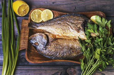 On a wooden table plate with two roasted carp fish dorado