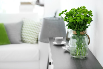 Beautiful green chrysanthemums in vase on commode in room