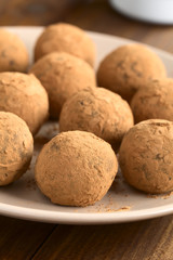 Homemade rum balls covered with cocoa powder, photographed with natural light (Selective Focus, Focus on the first ball)