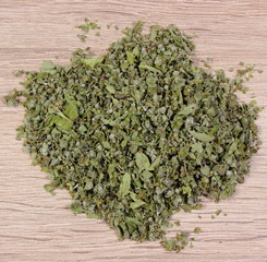 Heap of dried green marjoram on wooden background
