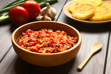 Colombian hogao or criollo sauce (salsa criolla) made of cooked onion and tomato, photographed on dark wood with natural light (Selective Focus, Focus in the middle of the sauce)