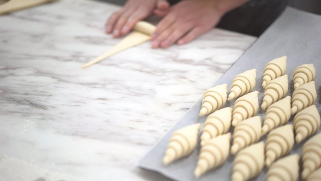 Close up of hand preparing croissant for baking