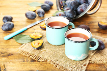 Plum Juice in mugs with fresh fruits