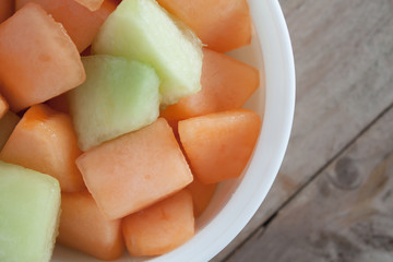 closeup melon slice in white dish with wood table background