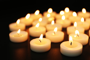 Obraz na płótnie Canvas Alight candles in a row on black background, blurred