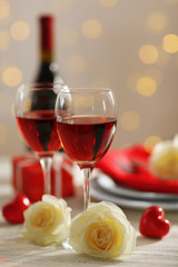 Setting of glasses with wine, bottle and a gift in the box, on white blurred background