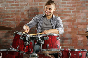 Musician playing the drums on brick wall background