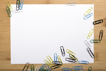 paper clips and blank paper on wooden background