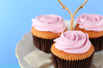 Tasty cupcakes on stand, on color background