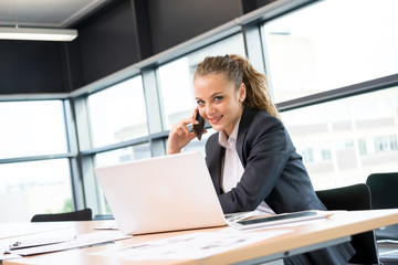 Businesswoman working & sitting at her desk in an office