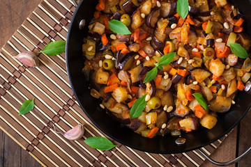 Italian Caponata with frying pan on a wooden background