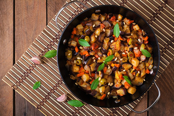 Italian Caponata with frying pan on a wooden background
