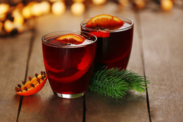 Mulled wine with spices and Christmas tree on wooden background