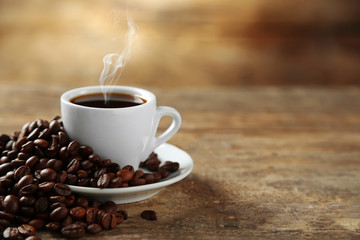 Cup of coffee and coffee grains on wooden background