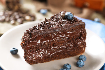 Chocolate cake with chocolate cream and fresh blueberries on plate, on wooden background