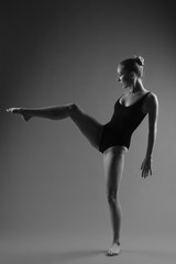 Modern ballet dancer posing on dark background