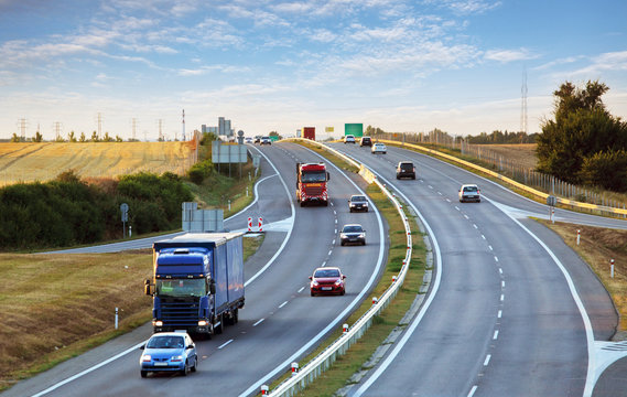 Highway traffic in sunset with cars and trucks