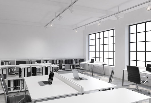 Workplaces in a bright modern loft open space office. Tables equipped with laptops; corporate documents' shelves. White copy space in the panoramic windows. 3D rendering.