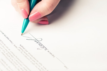 female hand signing a contract.