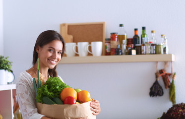 Young woman holding grocery shopping bag with vegetables 