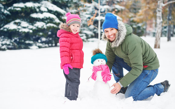 Happy family father and child girl makes snowman in winter
