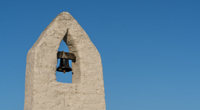 Small bell tower with a bell of a Welsh country chapel, against a deep blue sky