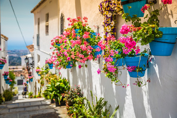 Picturesque street of Mijas with flower pots in facades. Andalus - obrazy, fototapety, plakaty
