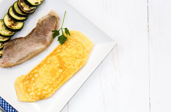 Combination plate of steak with omelette and vegetables