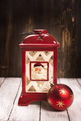 Christmas card. Red xmas lantern and ball over old wooden background. Toned image. Sselective focus