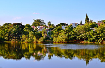 Fototapeta na wymiar Tropical landscape with trees, lake, blue sky and reflection in water