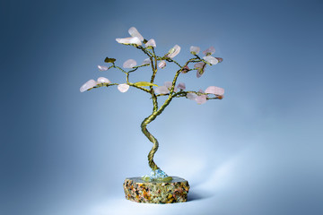 Tree from rose quartz on stone base and dark background