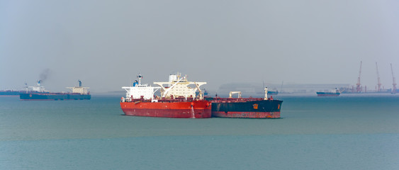 Loading anchored oil supertanker via a ship-to-ship oil transfer