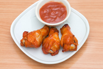 Chicken wings with sauce in dish on wooden table.