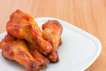 Chicken wings in dish on wooden table.
