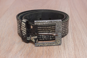 leather belt with a buckle on a wooden board