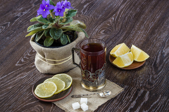 Black tea in old-fashioned glass with lemon on dark background