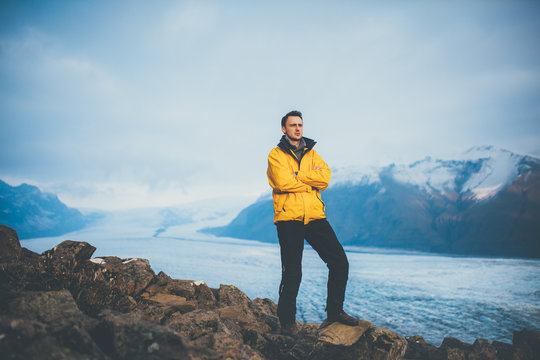 Young man wearing a yellow winter jacket standing at Vatnajokull glacier. Hiking on glacier