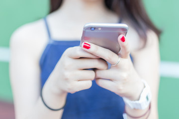 asian girl red nail using smartphone on tennis court