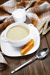 Vegetable soup with a spoon and a glass of milk on a wooden tabl