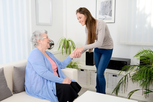 cheerful young girl taking care of old senior woman at home