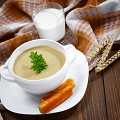 Vegetable soup with parsley and fried bread on a wooden table.